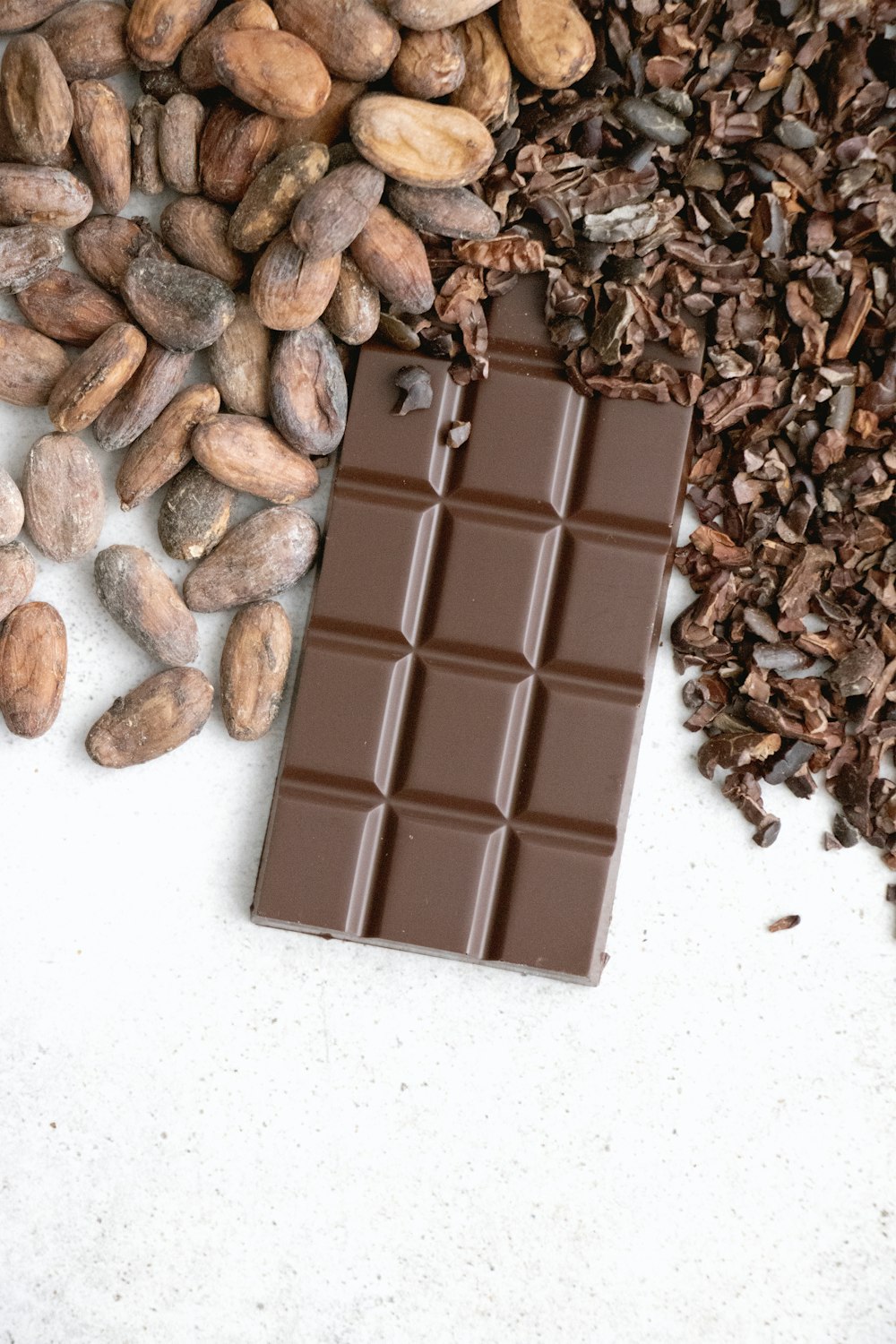 Finished dark chocolate bar made with Cocoa Merchant cocoa, alongside roasted cocoa beans